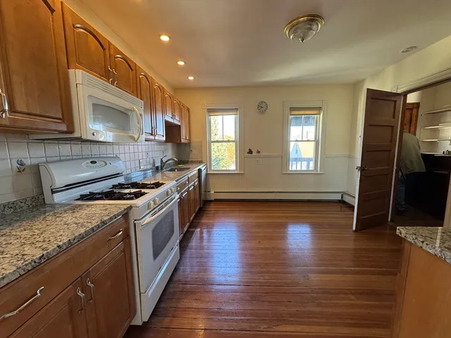 a large kitchen with stainless steel appliances granite countertop a stove a sink and a wooden floors