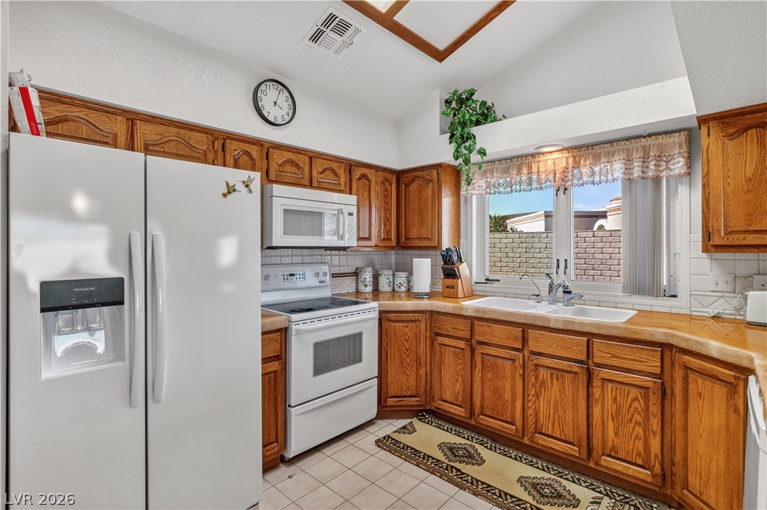 2055 Cholla Way Laughlin, NV 89029 - Photo 14 of 87 A well-equipped kitchen features white appliances complemented by warm wood cabinetry and neutral tile flooring.