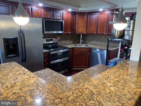a kitchen with stainless steel appliances kitchen island granite countertop a refrigerator and a sink