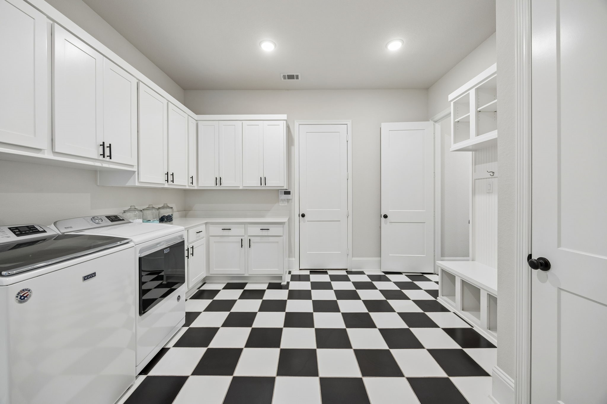 10102 South Goshawk Trail Conroe, TX 77385 - Photo 34 of 46 a kitchen with a checkered floor and white cabinets