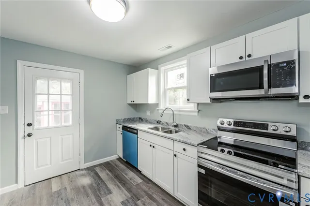 a kitchen with stainless steel appliances a stove a microwave and white cabinets