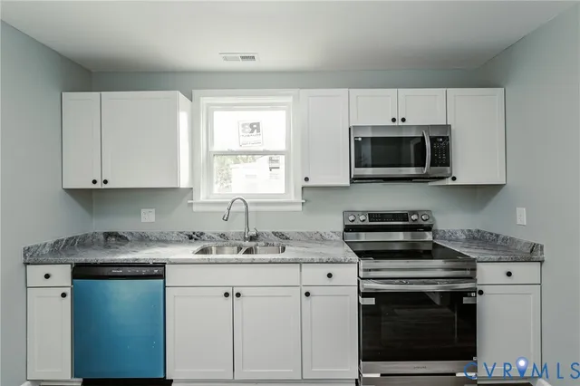 a kitchen with appliances a sink a stove a microwave and cabinets