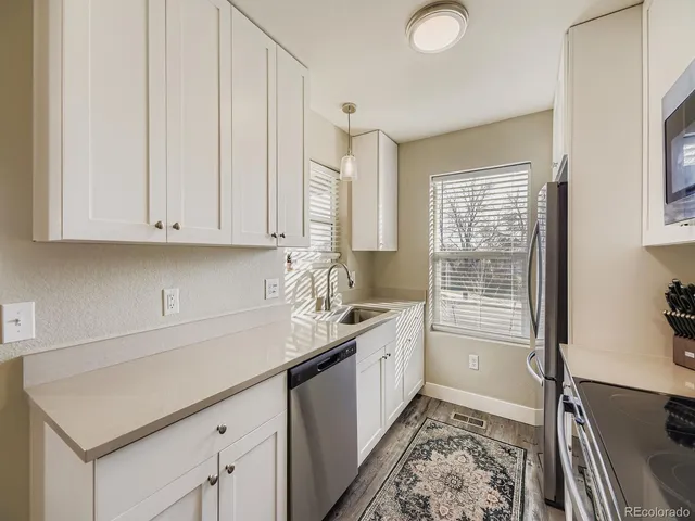a kitchen with stainless steel appliances granite countertop a sink and a white cabinets with wooden floor