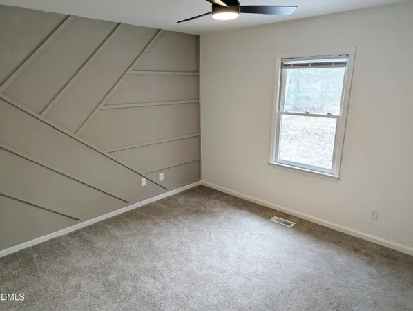 an empty room with a ceiling fan and window