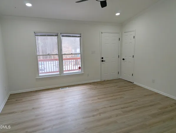 a view of an empty room with wooden floor and a window
