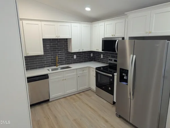 a kitchen with white cabinets and stainless steel appliances
