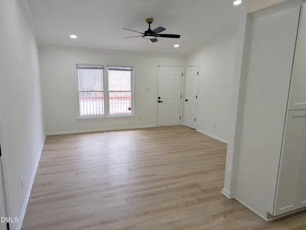 an empty room with wooden floor ceiling fan and windows