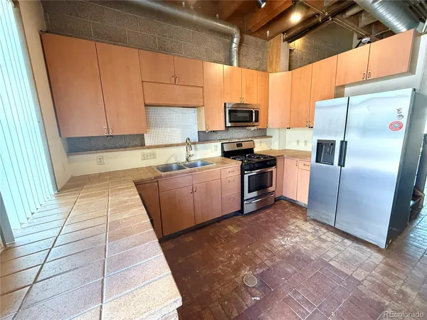 a large kitchen with stainless steel appliances granite countertop a stove a sink dishwasher and a refrigerator
