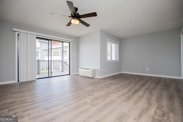 a view of empty room with wooden floor and fan