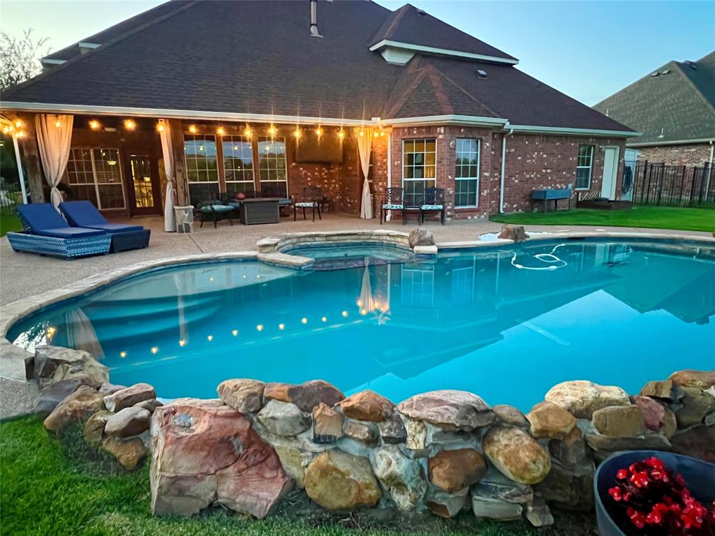 10414 Broadmoor Lane Rowlett, TX 75089 - Photo 1 of 38 Custom-shaped swimming pool with an integrated spa, bordered by a rock feature wall