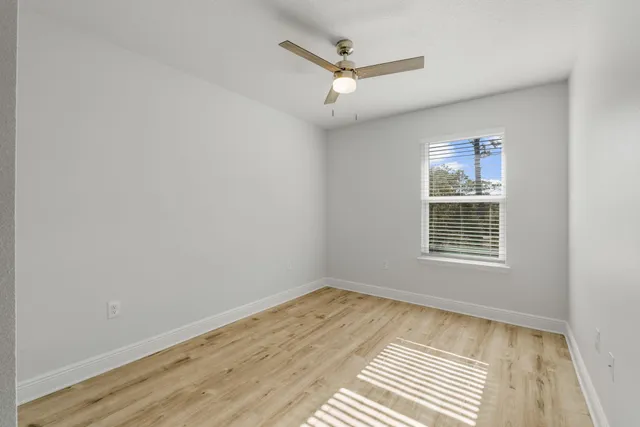 an empty room with a window and a ceiling fan