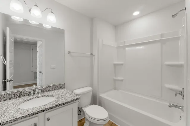 a bathroom with a granite countertop sink a toilet and shower