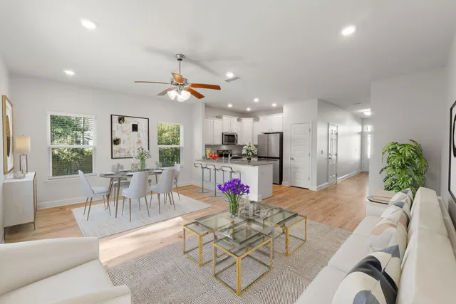 a kitchen with stainless steel appliances kitchen island granite countertop a refrigerator a stove a dining table and chairs with wooden floor