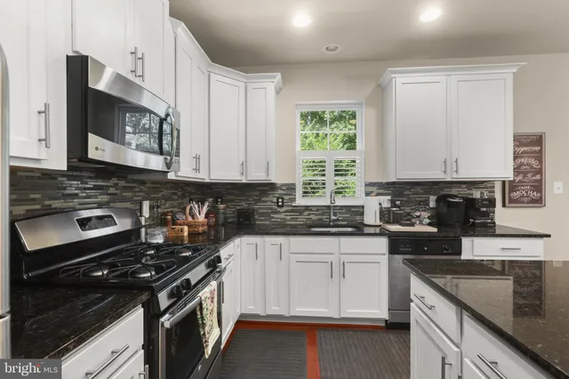 a kitchen with stainless steel appliances granite countertop white cabinets granite counter tops and a window