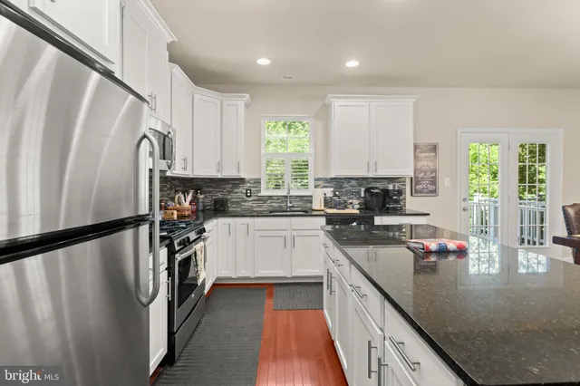 a kitchen with granite countertop a refrigerator a sink a stove and cabinets