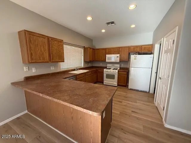 a kitchen with a refrigerator a stove top oven a sink and dishwasher with wooden floor