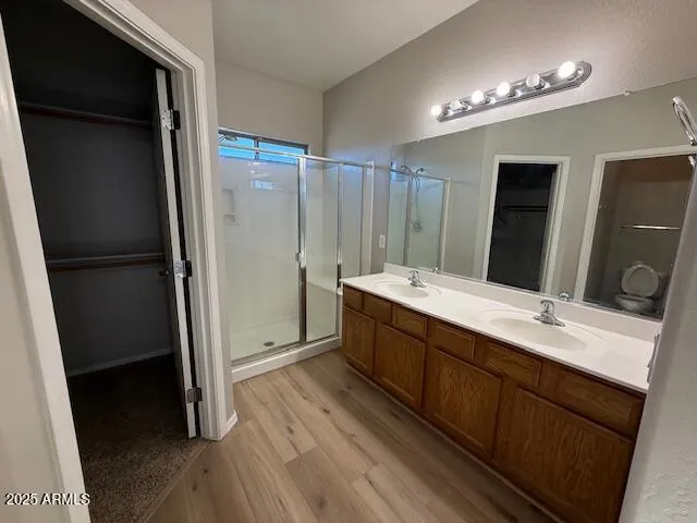 a bathroom with a double vanity sink a toilet a mirror and shower