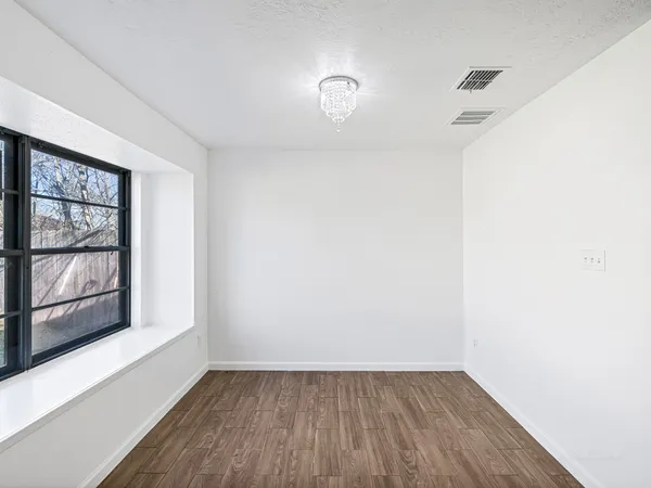 a view of an empty room with wooden floor and a window