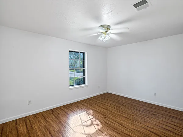a view of an empty room with a window and wooden floor
