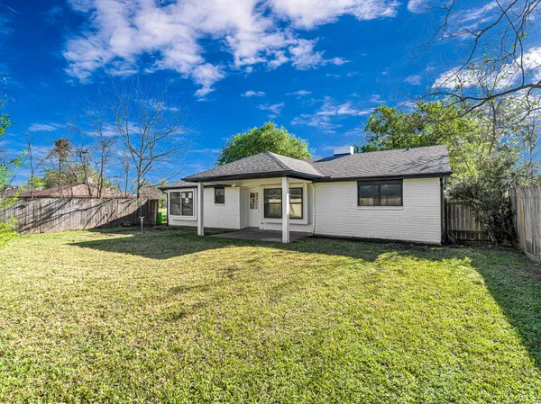 a backyard of a house with large trees and table and chairs