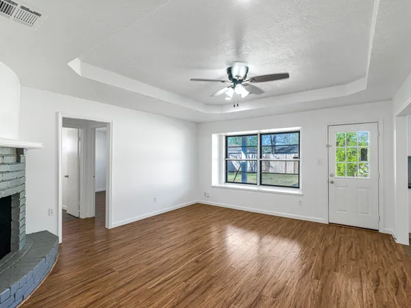 a view of an empty room with wooden floor and a window