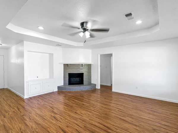 a view of an empty room with wooden floor fireplace and a window
