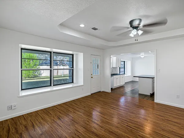 a view of empty room with wooden floor and fan