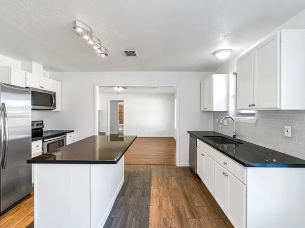 a kitchen with granite countertop a sink and stove top oven