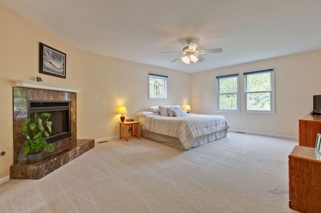 211 Washington Road Lake Forest, IL 60045 - Photo 10 of 26 a spacious bedroom with a bed and a fireplace