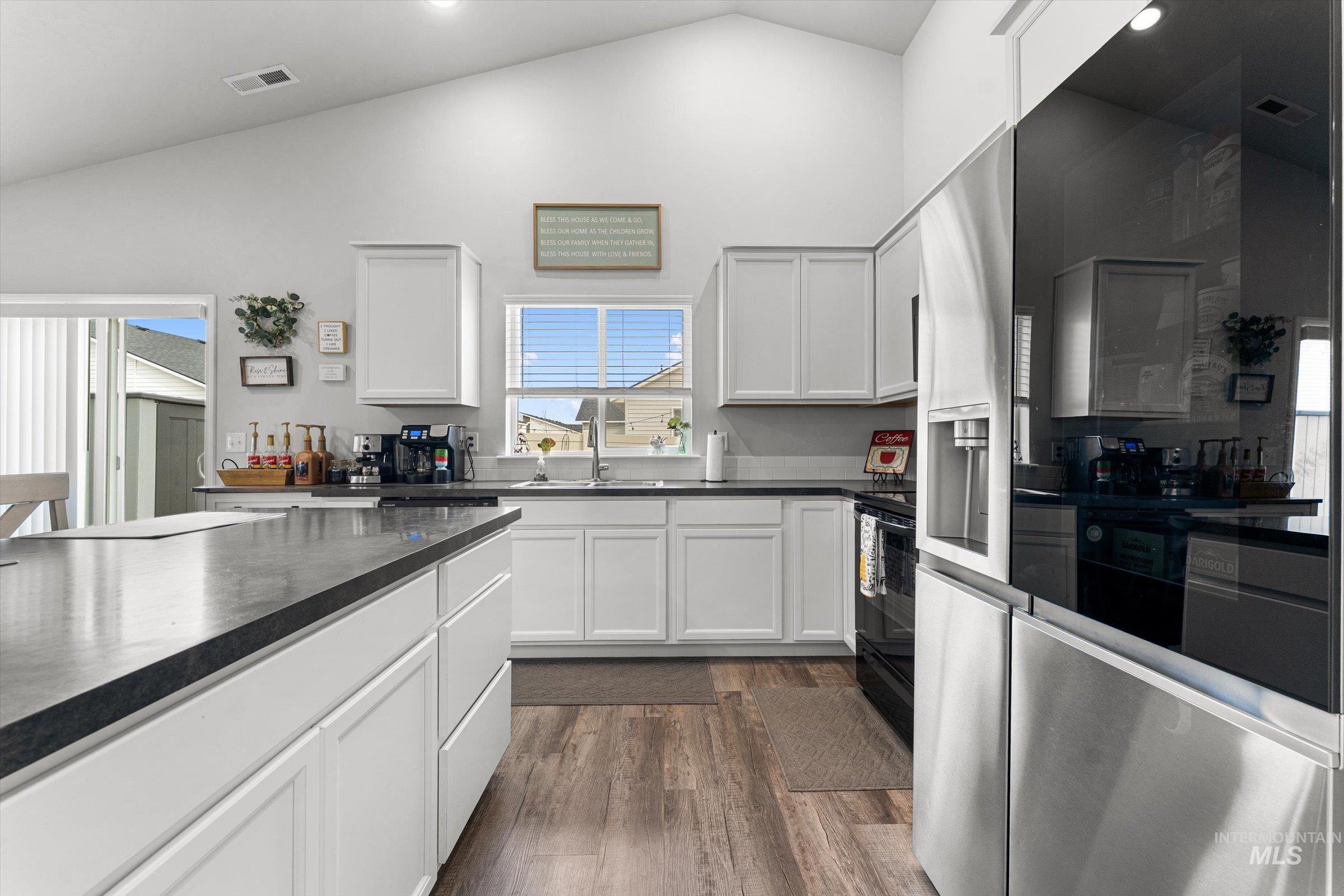 12798 Devonshire Street Caldwell, ID 83607 - Photo 15 of 42 Kitchen with stainless steel refrigerator with ice dispenser, white cabinetry, lofted ceiling, dark wood finished floors, and recessed lighting