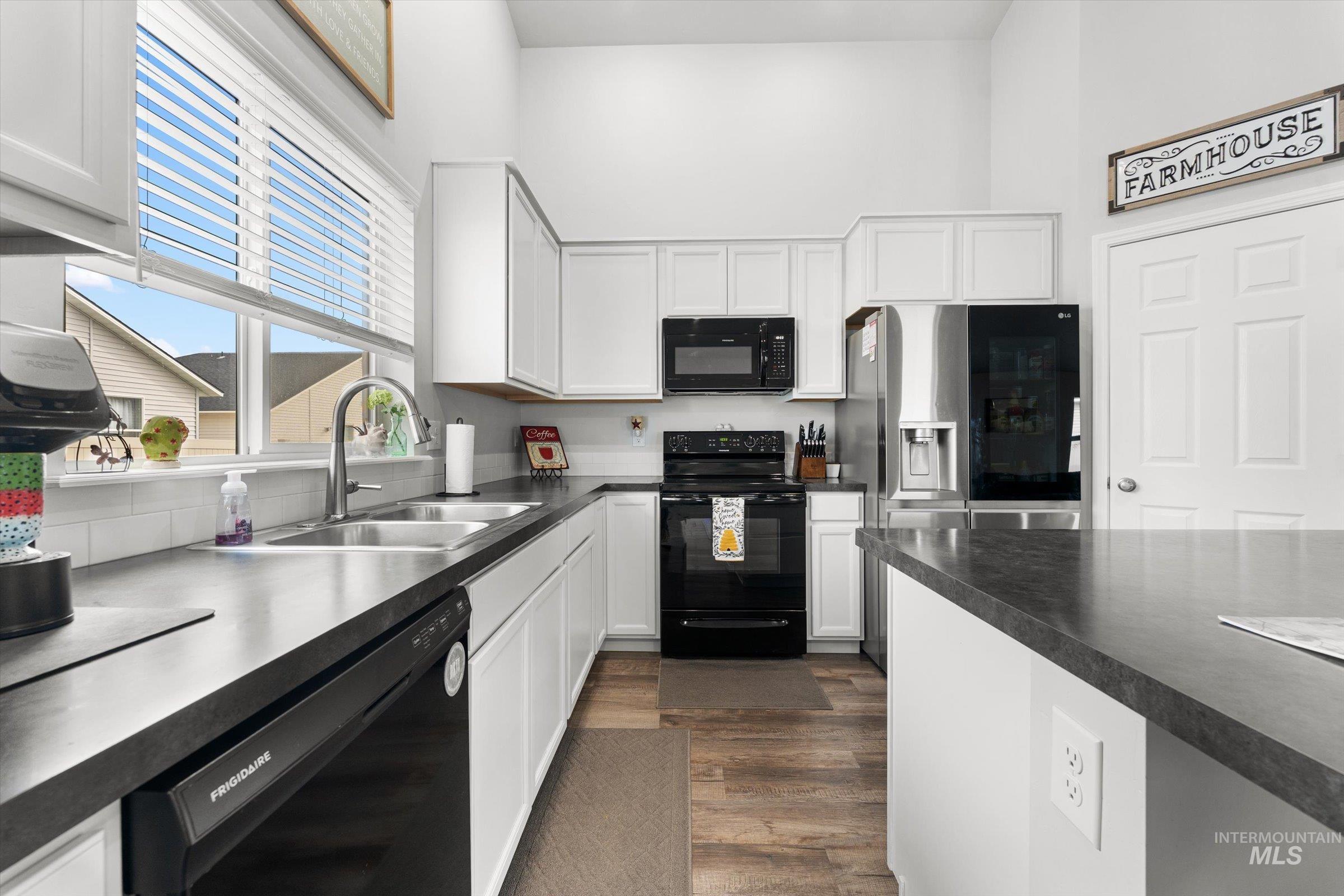 12798 Devonshire Street Caldwell, ID 83607 - Photo 16 of 42 Kitchen featuring a high ceiling, black appliances, white cabinets, dark countertops, and dark wood finished floors