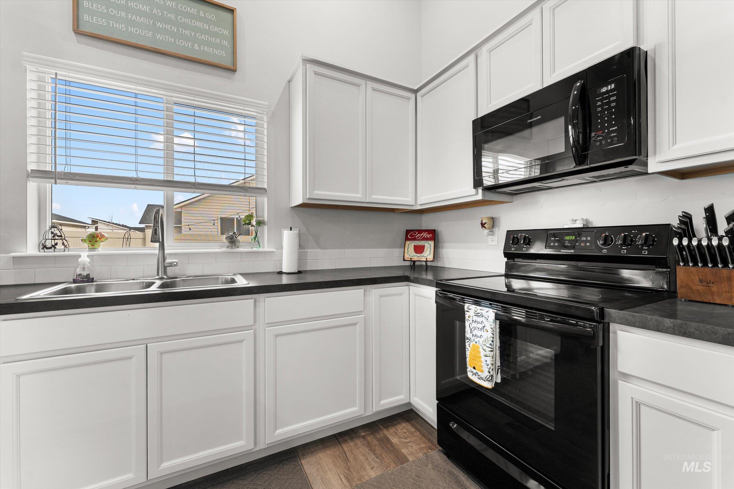12798 Devonshire Street Caldwell, ID 83607 - Photo 17 of 42 Kitchen featuring black appliances, white cabinets, dark countertops, and dark wood-style flooring
