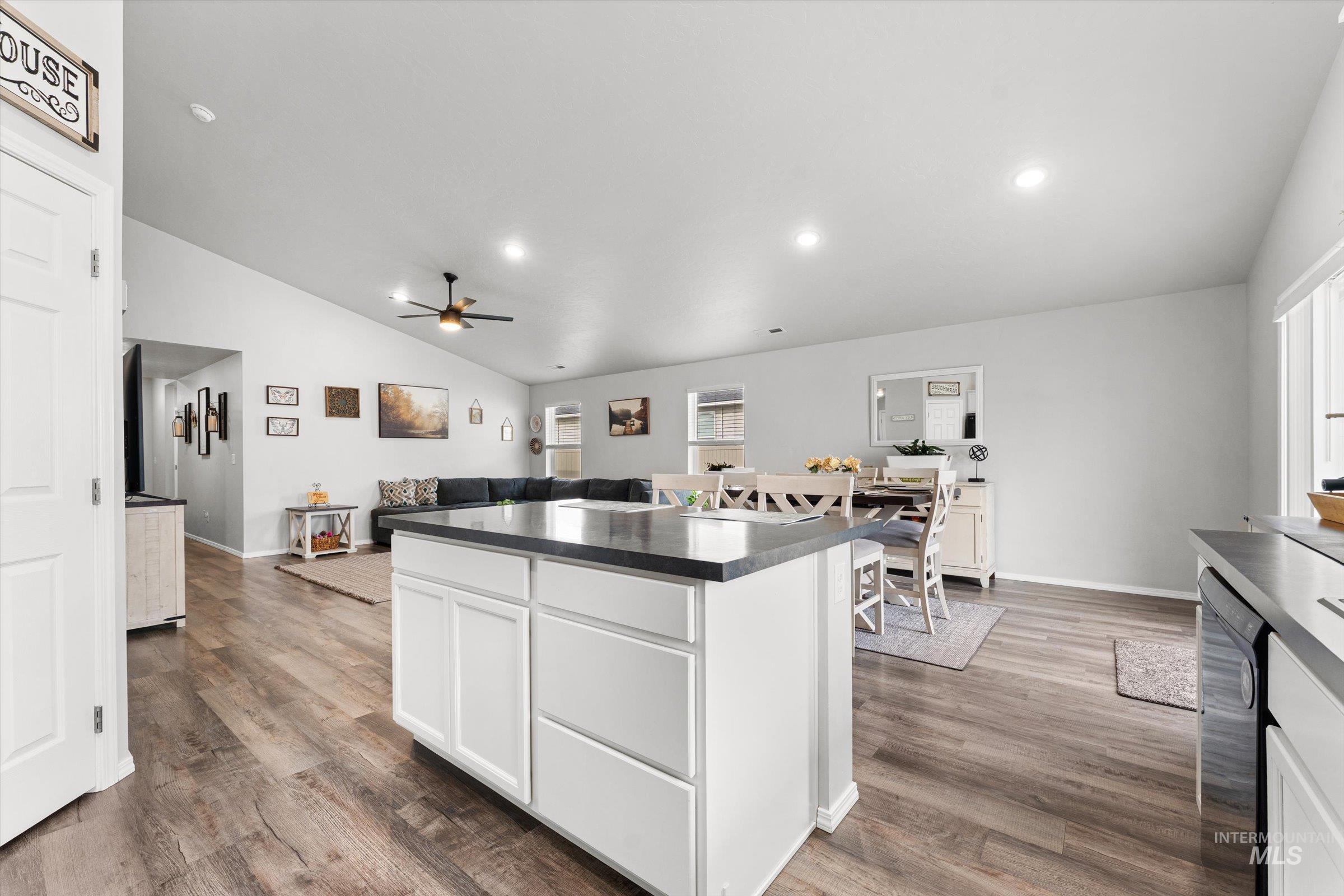 12798 Devonshire Street Caldwell, ID 83607 - Photo 42 of 42 Kitchen featuring dark countertops, vaulted ceiling, white cabinets, a center island, and open floor plan