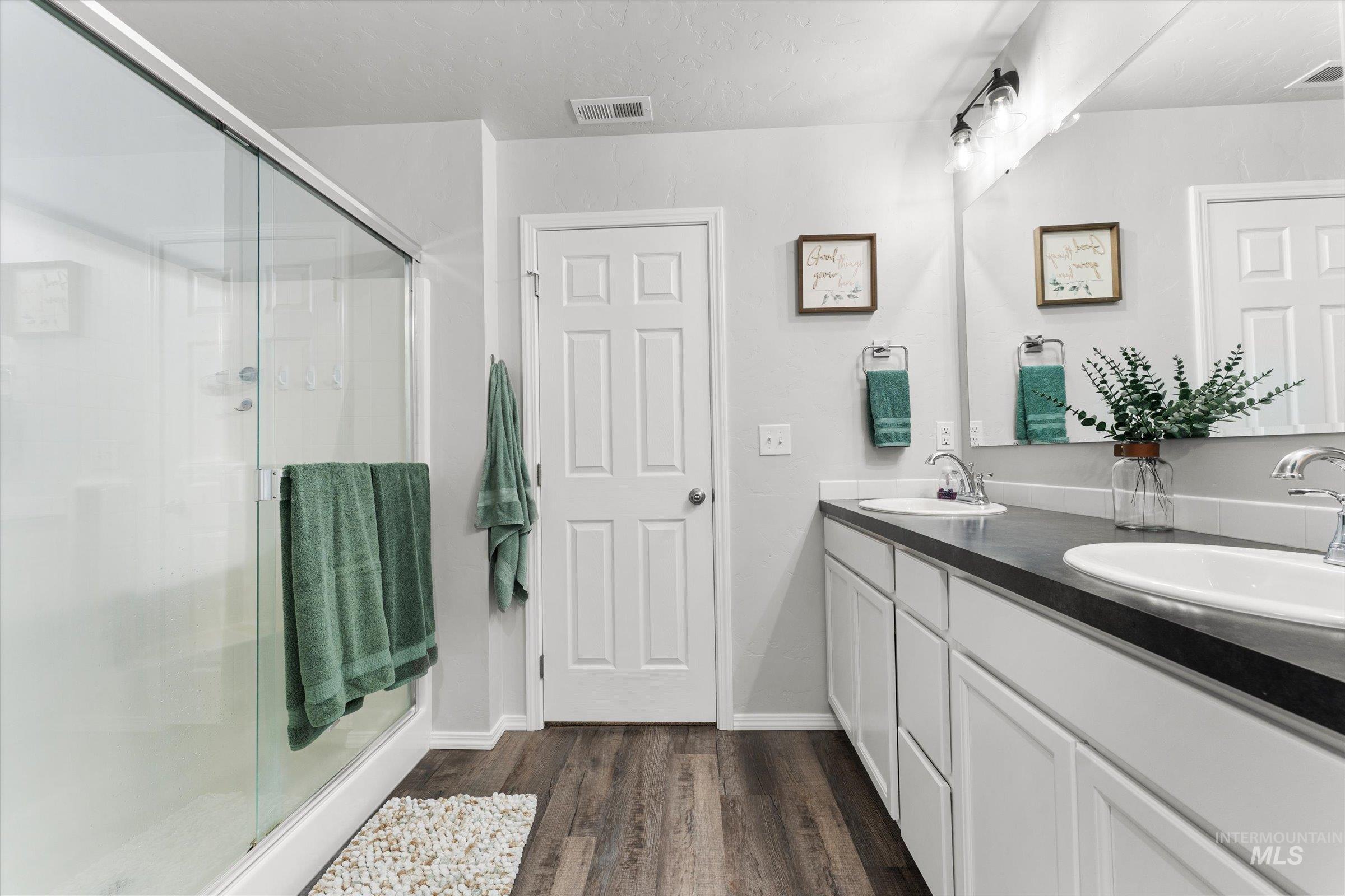 12798 Devonshire Street Caldwell, ID 83607 - Photo 27 of 42 Bathroom featuring a stall shower, double vanity, dark wood-type flooring, and a textured ceiling