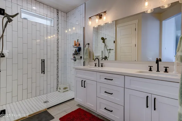 a bathroom with a double vanity sink mirror and shower