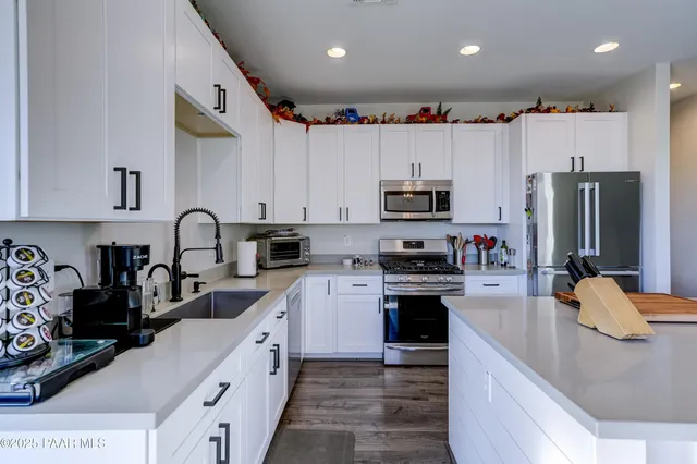 a kitchen with stainless steel appliances granite countertop a refrigerator a stove top oven a sink and dishwasher