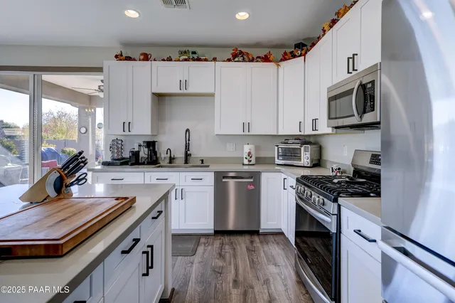 a kitchen with stainless steel appliances granite countertop a stove top oven a sink a counter space and cabinets