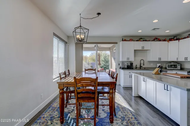 a kitchen with stainless steel appliances kitchen island granite countertop a dining table chairs and white cabinets