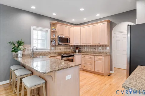 a kitchen with stainless steel appliances granite countertop a stove a sink a microwave a refrigerator and cabinets
