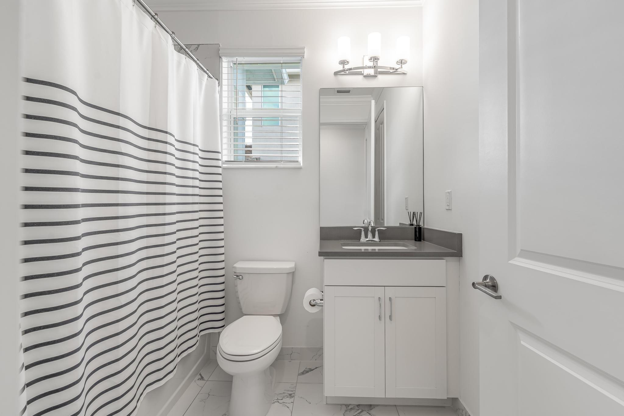 4164 Rosa Drive Deerfield Beach, FL 33064 - Photo 27 of 50 a bathroom with a granite countertop toilet sink and mirror