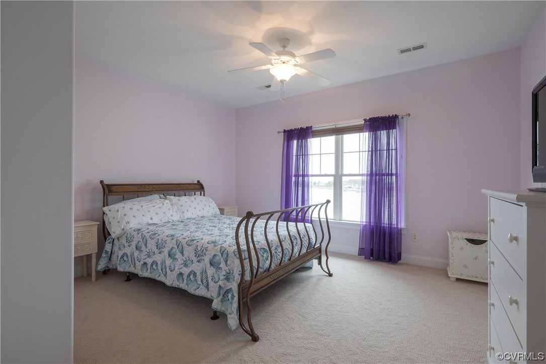 580 Riverside Drive Lancaster, VA 22503 - Photo 35 of 50 a spacious bedroom with a bed and a chandelier