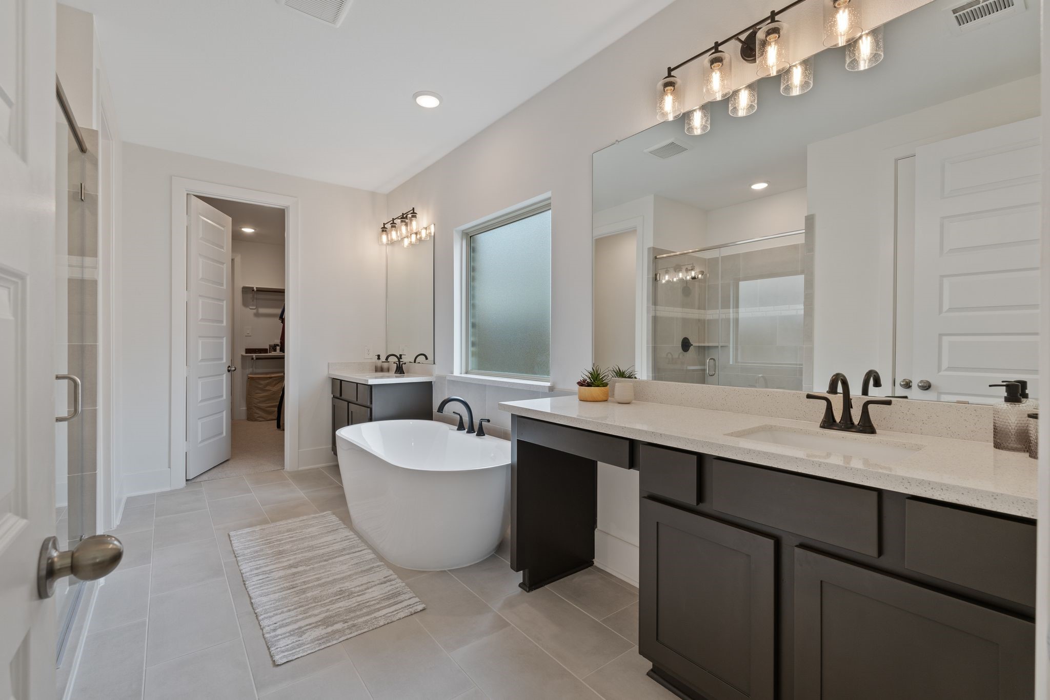 914 Sendero Trail Conroe, TX 77304 - Photo 19 of 50 Spa-like en-suite bathroom features dual sinks with vanity, freestanding tub and tile flooring.