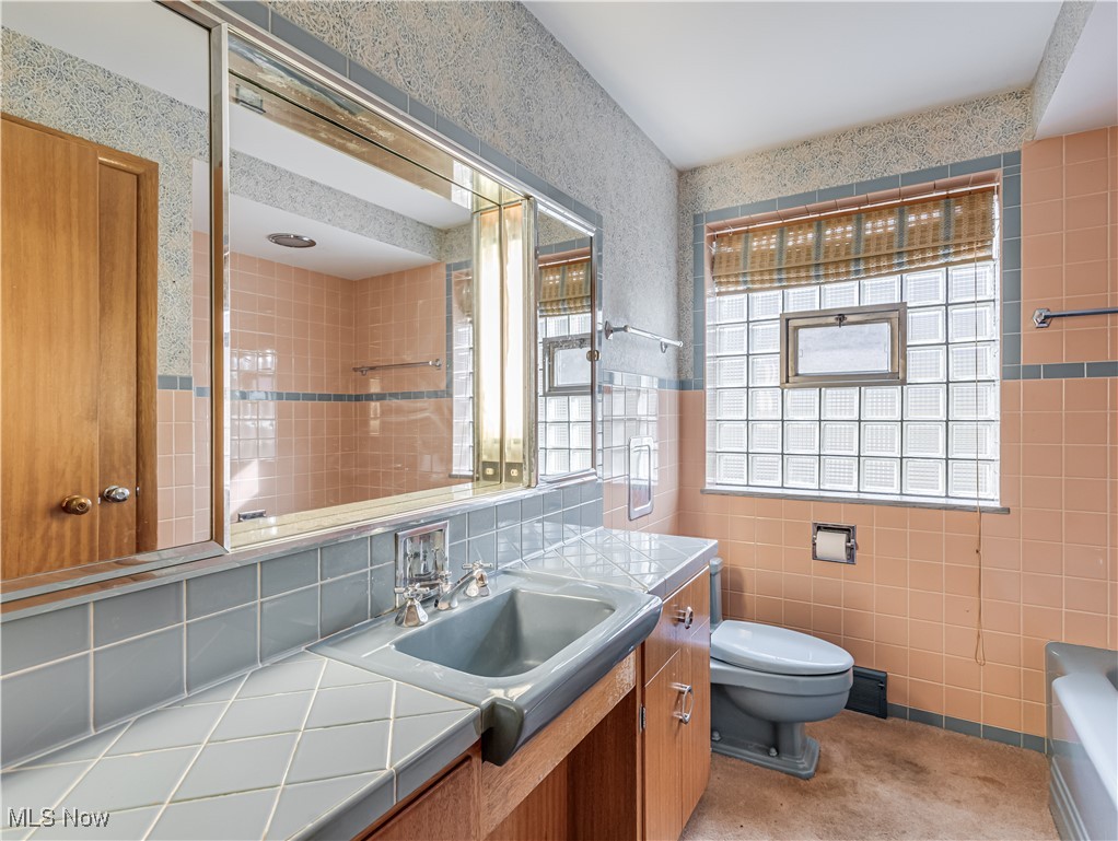 6576 State Road Wadsworth, OH 44281 - Photo 18 of 34 Bathroom with decorative backsplash, a washtub, vanity, tile walls, and toilet