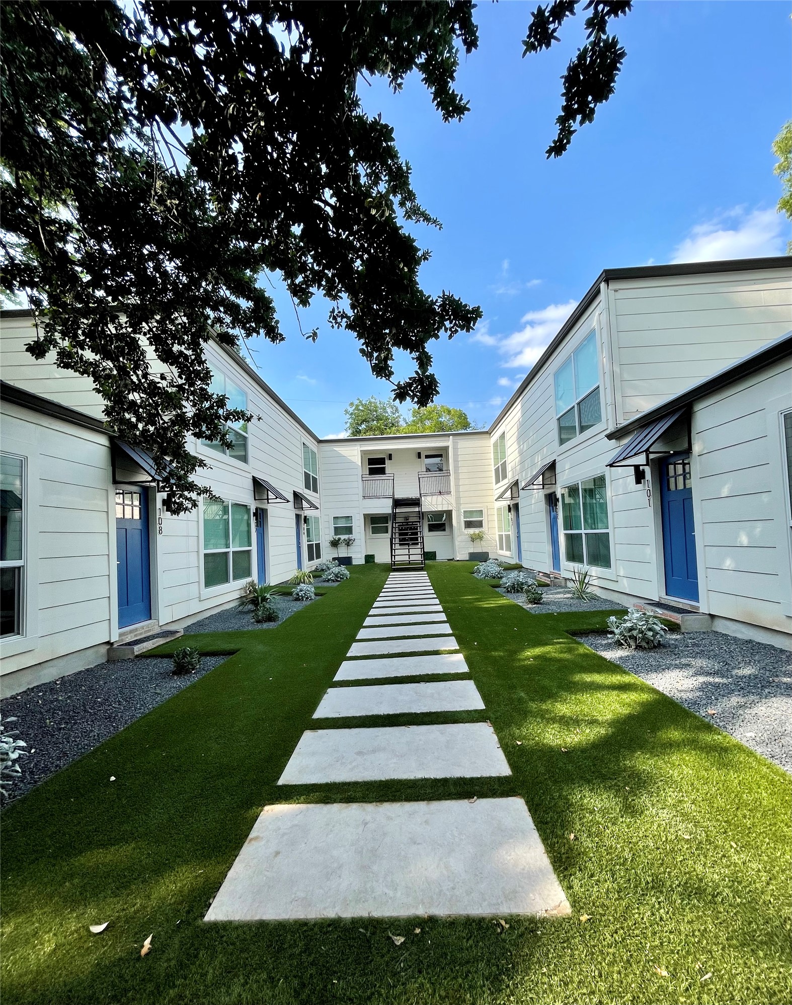1714 Enfield Road, Unit 102 Austin, TX 78703 - Photo 15 of 15 A vibrant green lawn and stepping stone pathway guide to modern apartment entrances.