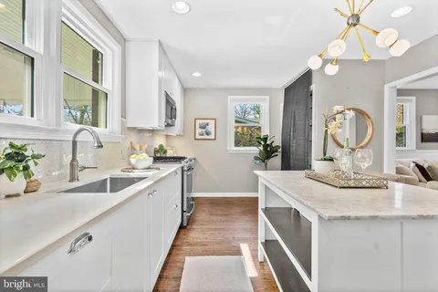 a large white kitchen with a stove a sink a window and dining table