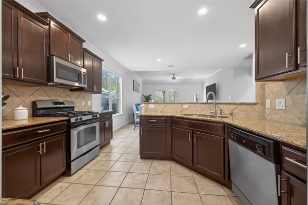 a kitchen with stainless steel appliances granite countertop wooden cabinets a stove top oven a sink and dishwasher