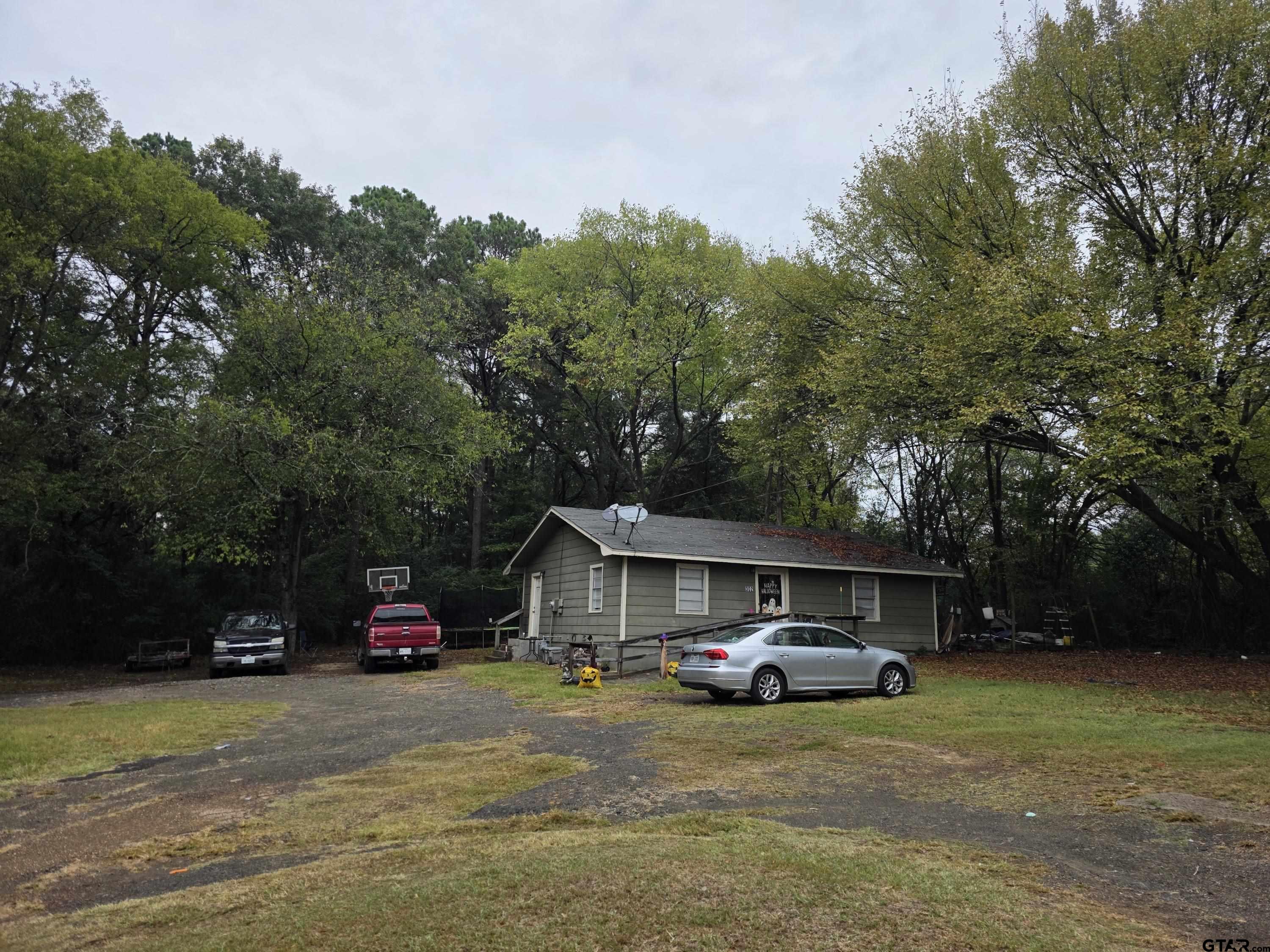 304 Walnut Street Naples, TX 75568 - Photo 2 of 28 a car parked in front of a house with big trees