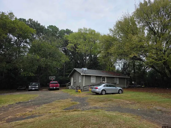 a car parked in front of a house with big trees