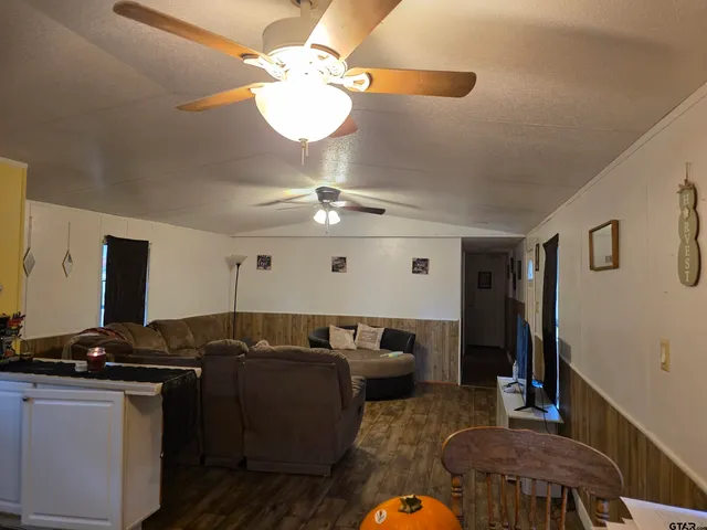a living room with large couches chandelier and a dining table with chandelier