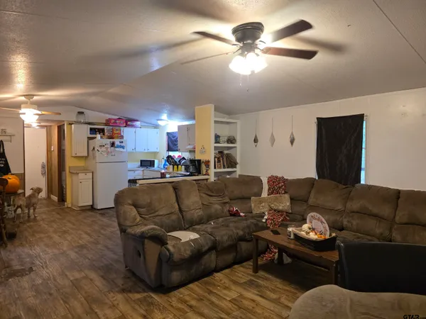 a living room with furniture kitchen view and a chandelier